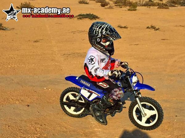 Dirt bike for kids in Dubai: small child in helmet and riding gear rides a blue Yamaha PW50 across the sand