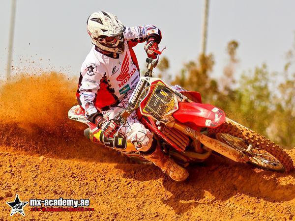 Motocross training in Dubai: rider with number 50 on a red Honda leans into a sandy corner, orange sand flying